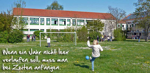 Kinder spielen auf Fußballplatz mit Slogan: Wenn ein Jahr nicht leer verlaufen soll, muss man bei Zeiten anfangen.