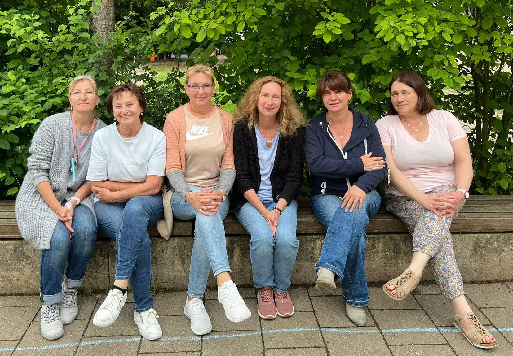 Das OGTS-Team der Grundschule Zeitlarn. 6 Mitarbeiterinnen des Teams sitzen auf einer Bank im Außenbereich der Schule.