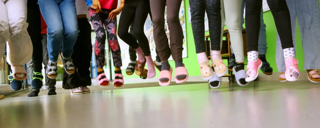 Eine Gruppe von Kindern springt in die Höhe. Sichtbar sind nur die Beine und Füße.