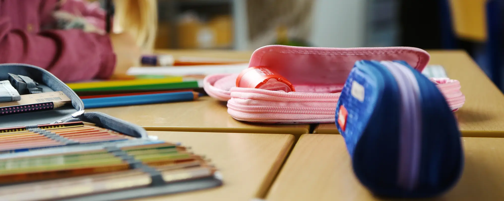Federmäppchen liegen auf einer Schulbank.