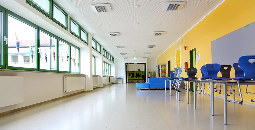 Schulflur der Grundschule Zeitlarn mit gelb gestrichender Wand und blauem Mobiliar.