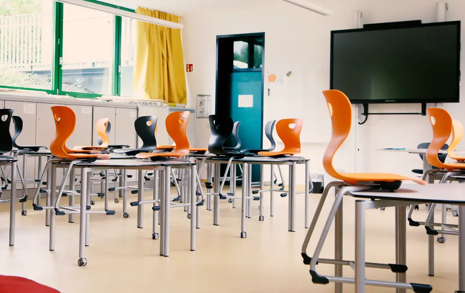 Der Handarbeitsraum der grundschule Zeitlarn. Schwarze und orange farbenen Stühle stehn auf Tischen.