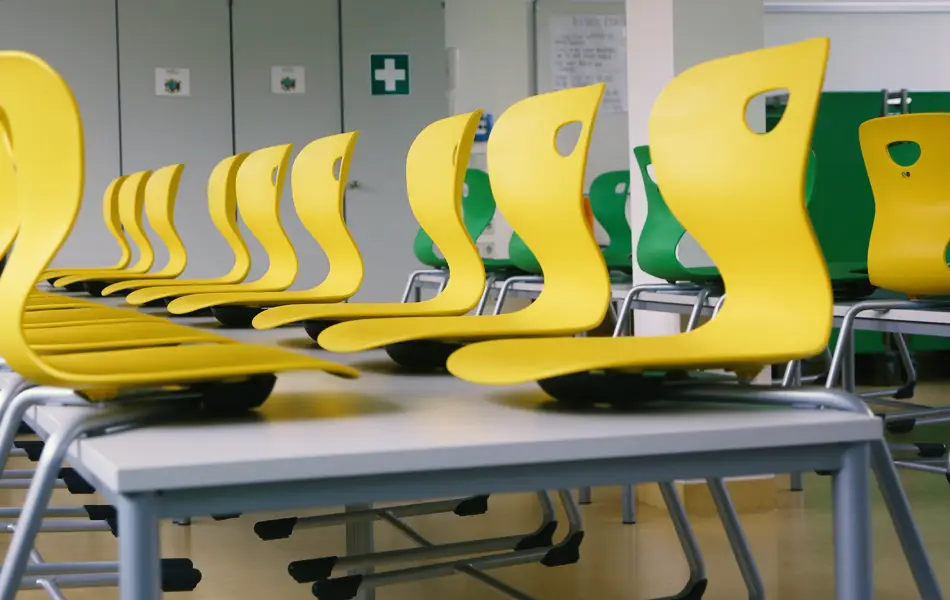 Bunte Bestuhlung in der Mensa. Grüne und gelbe Stühle stehen auf den Tischen.