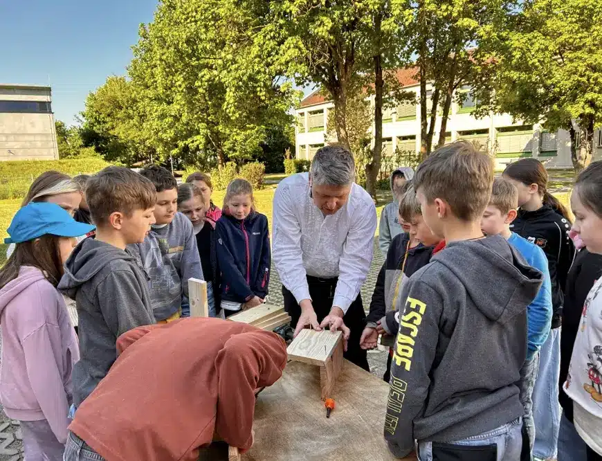 Kinder bauen unter Anleitung ein Vogelhaus aus Holz.