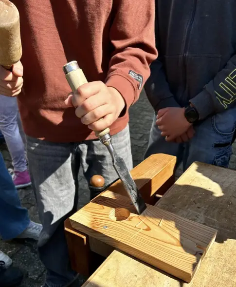 Kinder bauen unter Anleitung ein Vogelhaus aus Holz.