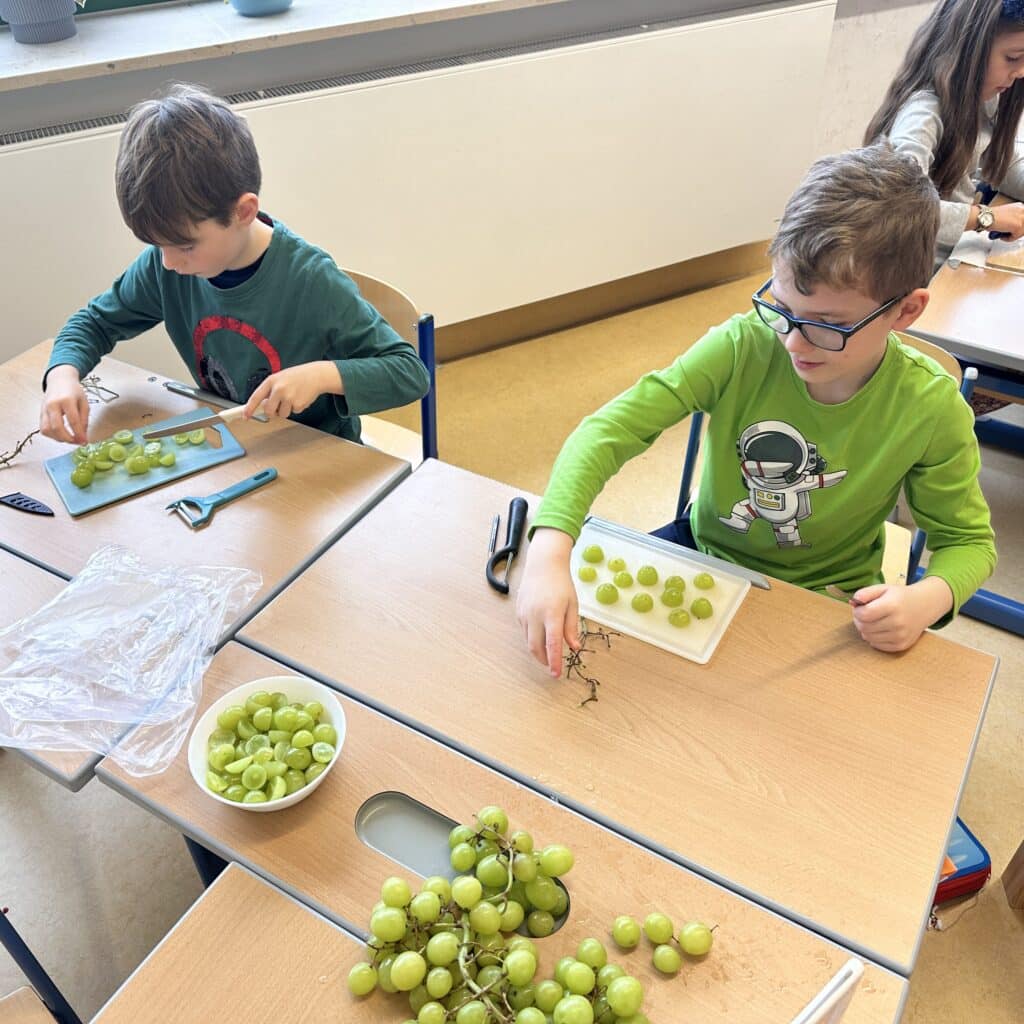 Schüler der Klasse 2b schneiden Obst für die Obstspieße her.