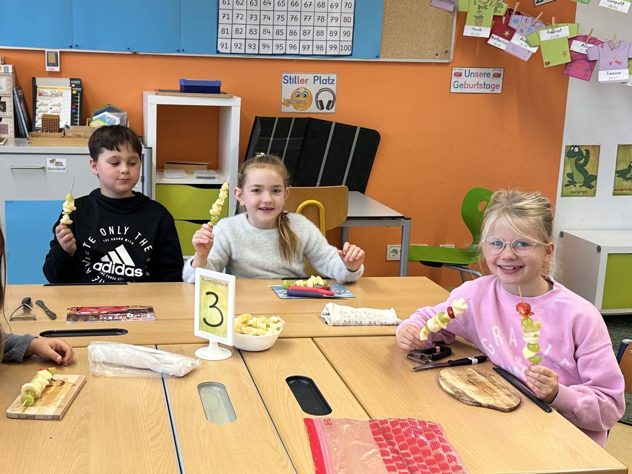 Stolz zeigen drei SchülerInnen ihre Obstspieße.